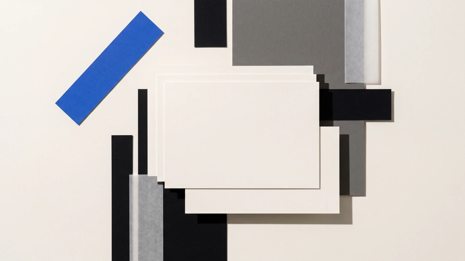 Des pièces de papier vierge disposées en escalier descendant, ombres dures projetées vers le bas à droite.