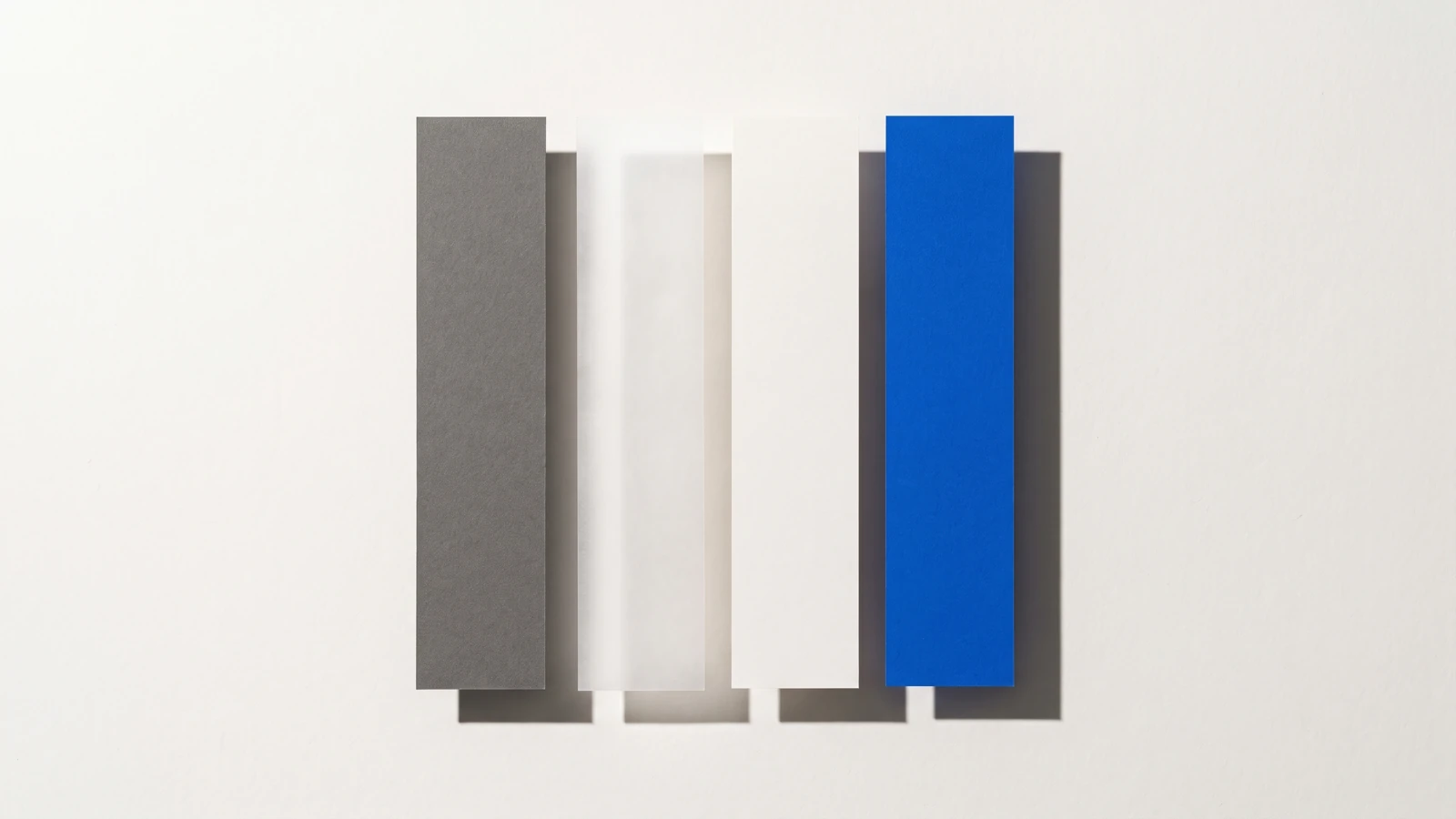 Une fenêtre rectangulaire découpée dans une plaque de carton gris laisse voir des cartes dessous, ombres dures projetées vers le bas à droite.