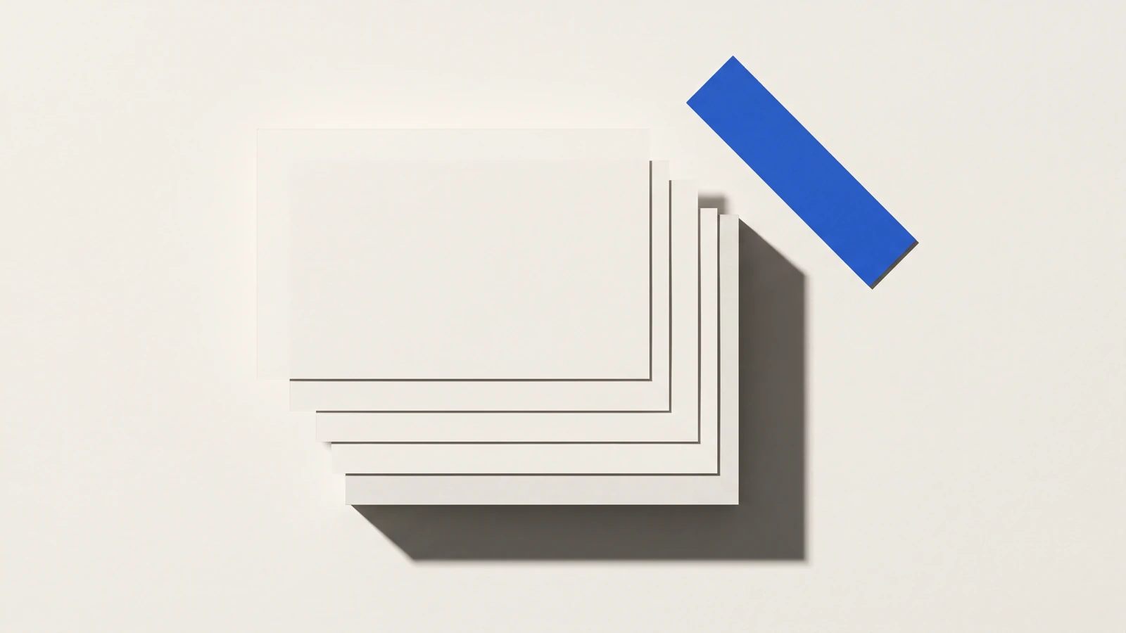Un calque cristal posé de biais sur des feuilles de papier vierge, ombres dures projetées vers le bas à droite.