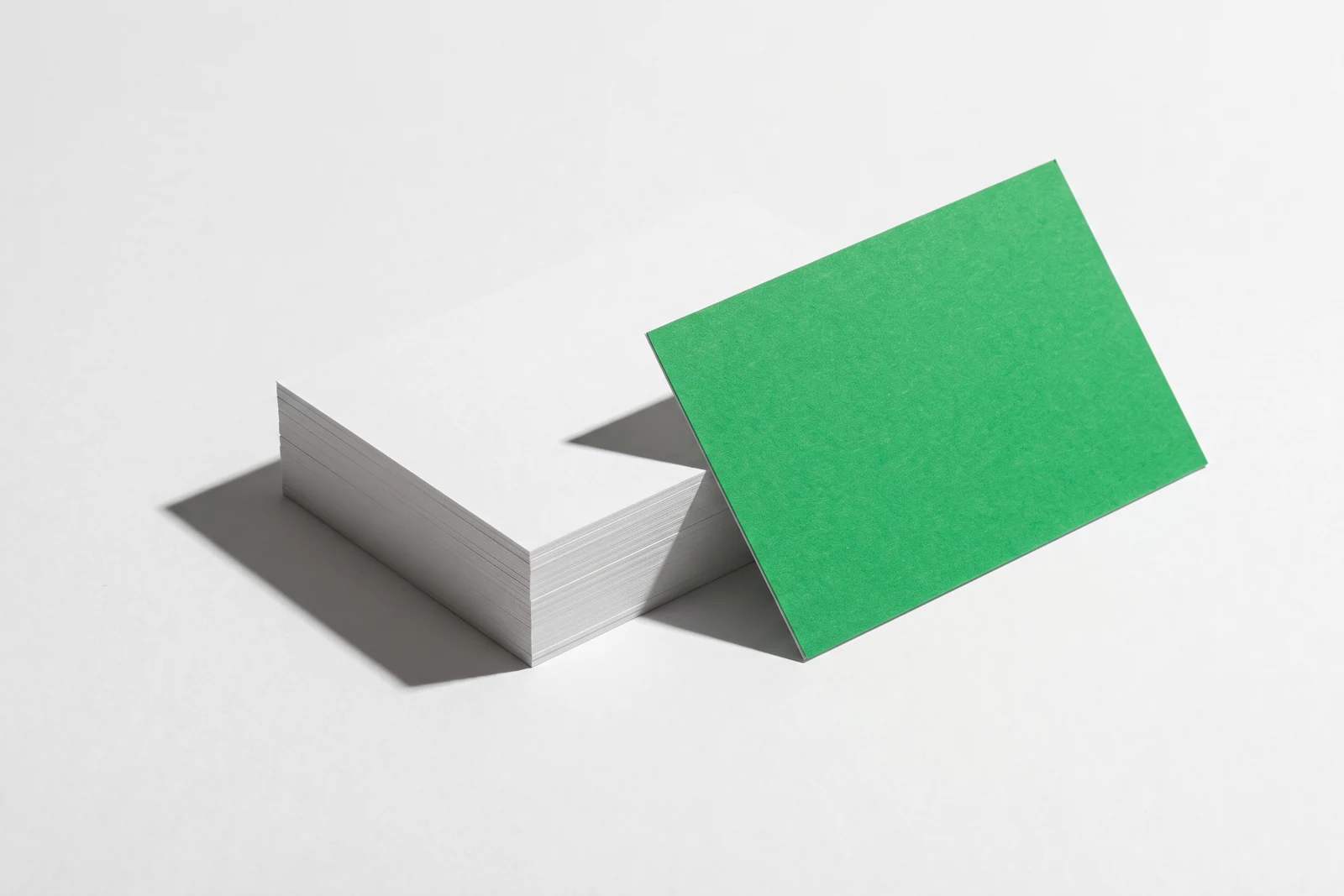 Une carte verte dressée sur chant, appuyée contre une pile de papier posée à plat