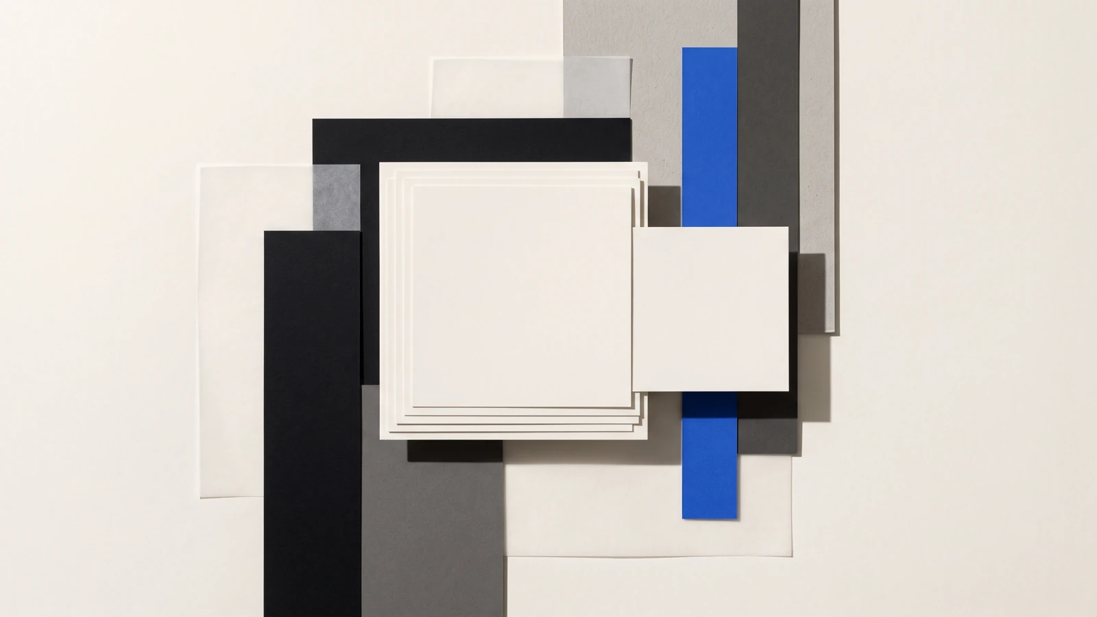 Des pièces de papier vierge disposées en escalier descendant, ombres dures projetées vers le bas à droite.