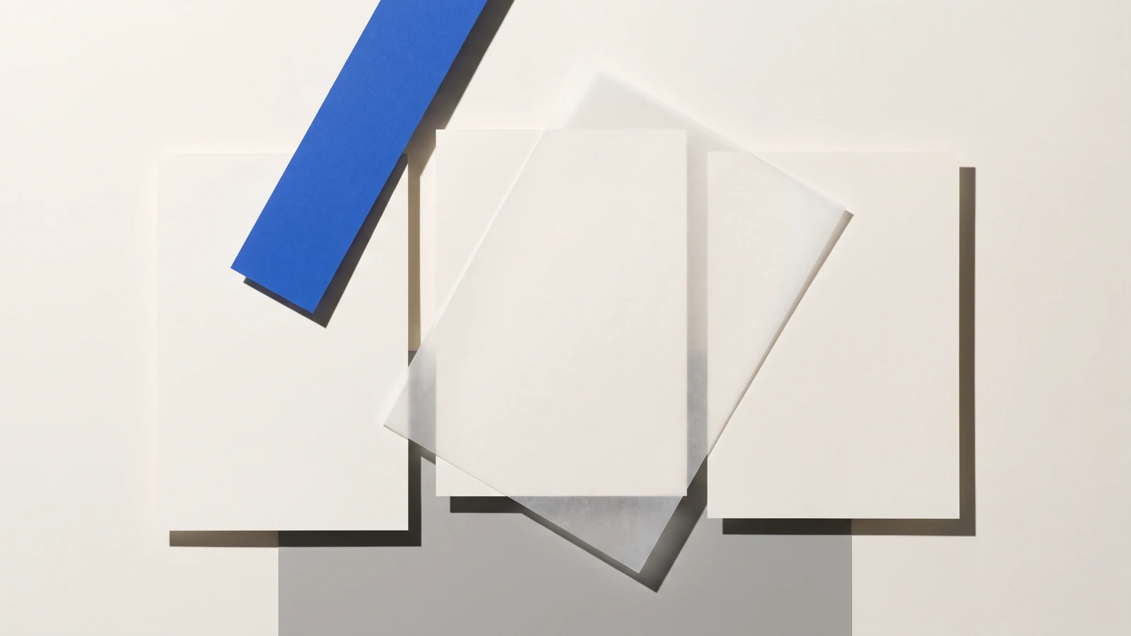 Une carte glissée hors d’une pile de papier vierge et qui dépasse nettement, ombres dures projetées vers le bas à droite.
