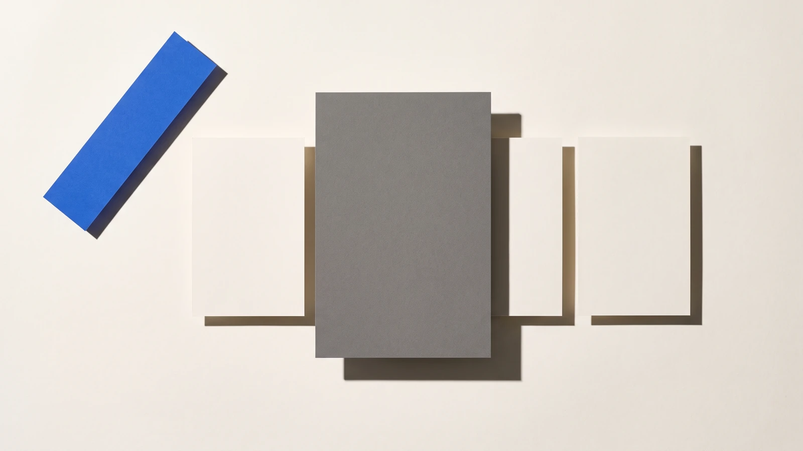 Une fenêtre rectangulaire découpée dans une plaque de carton gris laisse voir des cartes dessous, ombres dures projetées vers le bas à droite.
